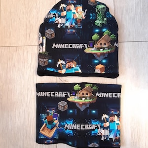 May include: Black Minecraft themed knit hat and neck warmer set. The hat and neck warmer feature a repeating pattern of Minecraft characters, blocks, and the word "Minecraft".