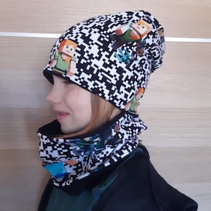 May include: Black and white beanie and neck gaiter with a pixelated design featuring characters from the video game Minecraft.