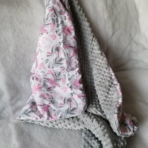 Pode incluir: Um cobertor macio para beb&eacute;, de cor cinzenta e branca, com um padr&atilde;o floral rosa e um lado cinzento texturizado.