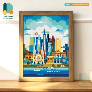 May include: A framed cross-stitch of the New York City skyline, featuring the Statue of Liberty and skyscrapers. The artwork uses a pixelated, colourful style. The frame is light-coloured wood, and the image is displayed on a wooden surface. The website address is visible.