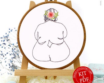 May include: An embroidery hoop with a minimalist line drawing of a figure wearing a floral headpiece. The hoop is displayed on a wooden easel, with embroidery supplies and the text "Awesome Pattern Studio" visible.