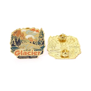 May include: Two gold-colored enamel pins. One pin features a landscape design with mountains, trees, and a bear, with the text "Glacier National Park." The other pin shows the back with two pin backs.