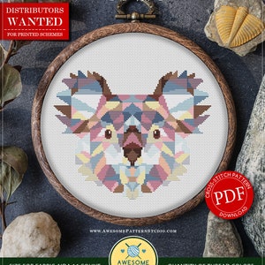 Op de afbeelding: Een kruissteekpatroon met een geometrisch koala-ontwerp in een houten borduurring. Het patroon gebruikt pastelkleuren. De tekst "COUNTED CROSS STITCH PATTERN FOR INSTANT DOWNLOAD" staat bovenaan. De patroongrootte is 18,57 x 15,24 cm.