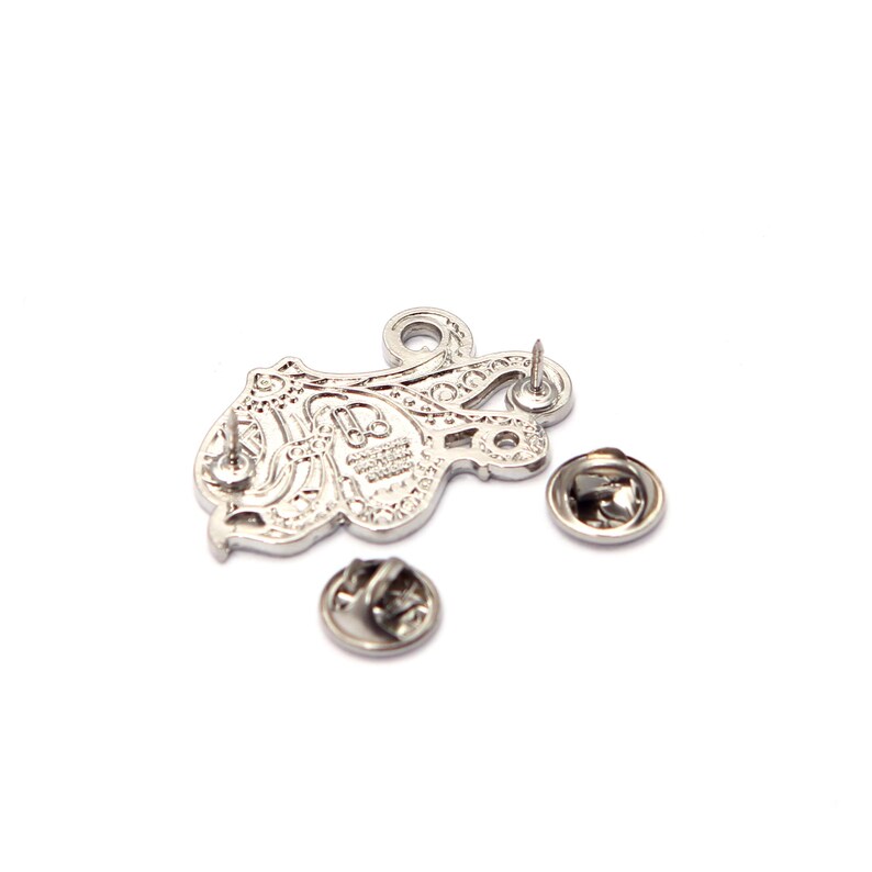 May include: Silver-colored octopus pin with intricate detailing. The pin features a classic pin back and two additional pin backs. The octopus design is visible, with a detailed pattern on its body. A stylish accessory for jackets, bags, or hats.