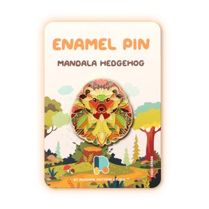 Puede incluir: Un pin de esmalte con un dise&ntilde;o de erizo mandala colorido. El pin se presenta sobre una tarjeta con el texto "ENAMEL PIN MANDALA HEDGEHOG" y una escena de bosque. El pin tiene una paleta de colores vibrantes de rojo, amarillo, verde y naranja.