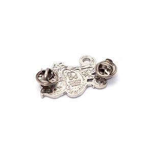 May include: A silver-colored metal pin with an ornate, swirling design. The pin has two pin backs for secure attachment. The design includes intricate details and a small loop at the top. The pin is likely a decorative accessory.
