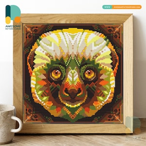 May include: A colorful pixel art image of a lemur's face. The lemur's fur is a mix of green, yellow, orange, and brown. The lemur has large, round, yellow eyes. The image is framed in a brown wooden frame.