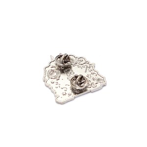 Pu&ograve; includere: Una spilla in metallo color argento con due fermagli. La spilla presenta un design dettagliato con elementi floreali e simili a ingranaggi. La spilla &egrave; su sfondo bianco.