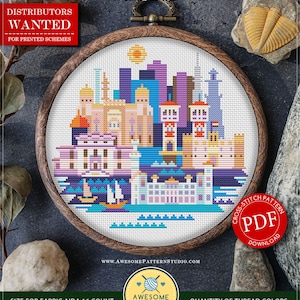 Könnte beinhalten: Gezähltes Kreuzstichmuster zum sofortigen Download, betitelt "Alexandria" mit einem farbenfrohen Stadtbild-Design. Das Muster ist 99 x 93 Stiche groß und misst 6,19 x 5,81 Zoll. Das Muster befindet sich in einem hölzernen Stickrahmen.