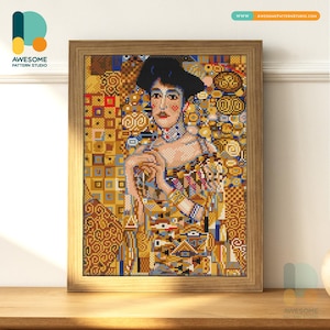 May include: Framed cross-stitch art featuring a portrait of a woman in a hat, with a detailed, colorful design. The artwork is in a wooden frame and is displayed on a wooden surface. The image includes the logo of Awesome Pattern Studio.