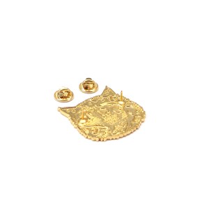 Puede incluir: Un pin met&aacute;lico dorado con forma de cabeza de gato, con dos cierres de alfiler. El pin tiene detalles intrincados y dos cierres de alfiler para una fijaci&oacute;n segura. El dise&ntilde;o de la cabeza de gato es visible en la parte delantera.