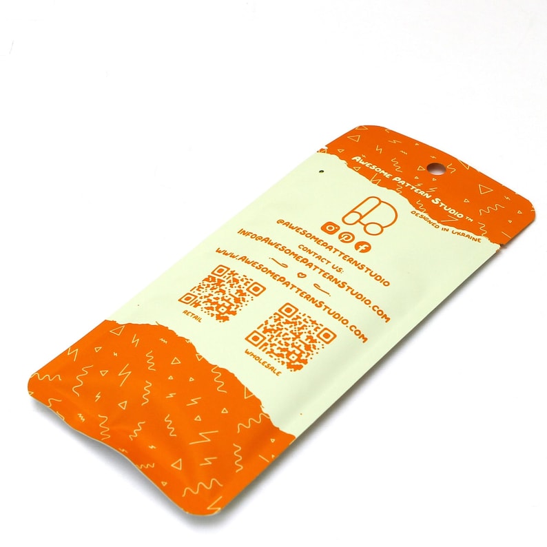 May include: A white and orange package with the text "AWESOME PATTERN STUDIO" and social media icons. The package has a small hole at the top and two QR codes. The design includes orange lightning bolt and triangle patterns.