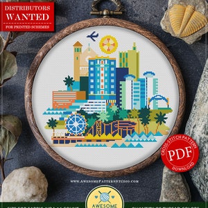 Peut inclure: Un modèle de point de croix compté pour Santa Monica, Californie, représentant une ville colorée avec des bâtiments, des palmiers et une grande roue. Le modèle est disponible en téléchargement PDF et est conçu pour du tissu Aida 16 fils. Le modèle nécessite 18 couleurs de fils DMC différentes.