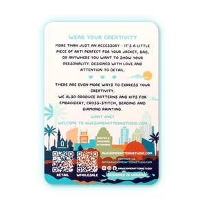 May include: A white card with text that reads "WEAR YOUR CREATIVITY" and "WELCOME TO AWESOMEPATTERNSTUDIO.COM". The card features a colorful skyline illustration and QR codes for retail and wholesale.
