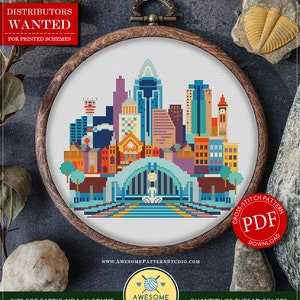 Könnte beinhalten: Gezähltes Kreuzstichmuster für Cincinnati, Ohio, mit einer farbenfrohen Stadtlandschaft mit einer Brücke und Gebäuden. Das Muster ist als PDF-Download erhältlich und für Aida-Stoff mit 16 Fäden ausgelegt. Das Muster verwendet 18 DMC-Farben.