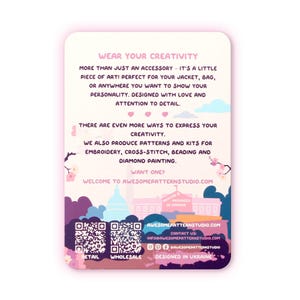 May include: A rectangular card with rounded corners, featuring text that reads "WEAR YOUR CREATIVITY." The card promotes embroidery, cross-stitch, beading, and diamond painting kits. It includes a website address and social media handles.