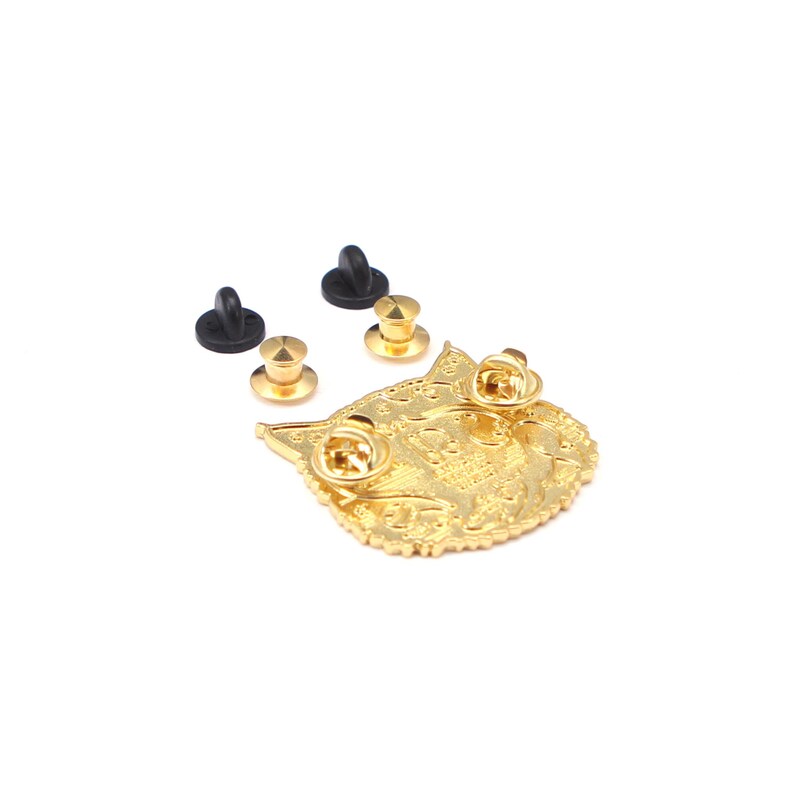 Puede incluir: Un pin de metal dorado con forma de cara de gato, con dos cierres de alfiler adjuntos. Tambi&eacute;n se incluyen dos cierres de alfiler de goma negra adicionales y dos cierres de alfiler dorados. El pin tiene detalles intrincados.