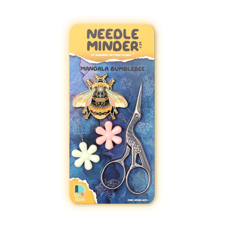May include: A craft set featuring a mandala bumblebee needle minder, a pair of silver embroidery scissors, and three flower-shaped stitch markers. The packaging has the text "Needle Minder Set" and "Mandala Bumblebee". The background is blue with floral patterns.