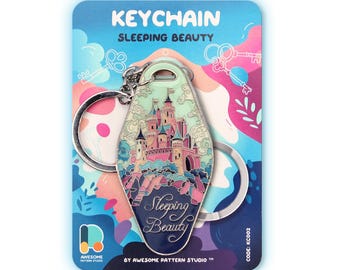 May include: A motel-style keyring featuring a Sleeping Beauty castle illustration in pink, blue, and cream colours. The keyring has a metal ring and is attached to a backing card with the text KEYCHAIN SLEEPING BEAUTY and AWESOME PATTERN STUDIO.