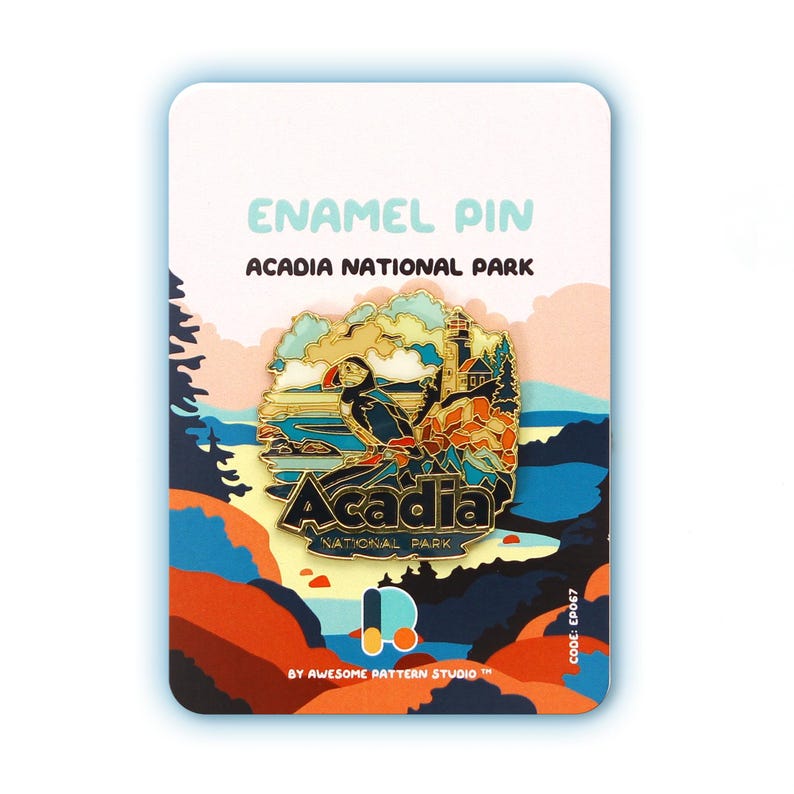 K&ouml;nnte beinhalten: Ein farbenfroher Emaille-Pin mit dem Acadia National Park, der einen Papageientaucher, einen Leuchtturm und den Parknamen zeigt. Der Pin befindet sich auf einer wei&szlig;en Karte mit dem Text "ENAMEL PIN ACADIA NATIONAL PARK" und "BY AWESOME PATTERN STUDIO".
