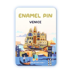 Könnte beinhalten: Emaille-Anstecknadel mit einer goldenen Darstellung der venezianischen Architektur, einschließlich Kuppeln und einer Gondel. Die Nadel befindet sich vor einem hellblauen Hintergrund mit den Worten "ENAMEL PIN" und "VENICE". Die Nadel befindet sich auf einer Karte mit einer farbenfrohen Illustration.