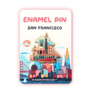 Op de afbeelding: Een emaille pin met een San Francisco thema. De pin toont de Golden Gate Bridge, een kabeltram en stadsgebouwen. De pin zit op een kaart met de tekst "ENAMEL PIN SAN FRANCISCO" en "BY AWESOME PATTERN STUDIO".