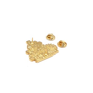May include: A gold-colored metal pin with a detailed circuit board design. The pin has two pin backs and a pin post. The pin is on a white background.