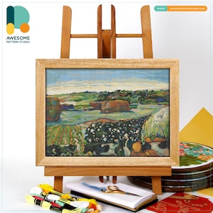 Può includere: Una scena di paesaggio a punto croce incorniciata in una cornice di legno chiaro, esposta su un cavalletto di legno. L'opera raffigura un campo con alberi e uno specchio d'acqua. Fili da ricamo, forbici e un taccuino sono in primo piano. Il sito web è visibile.