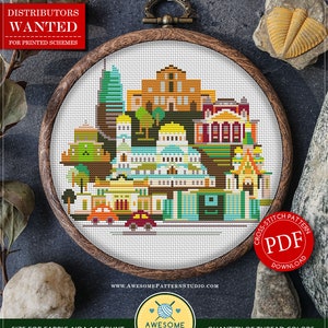 May include: Counted cross stitch pattern for instant download, featuring a colorful cityscape with buildings and cars. The pattern is in a wooden embroidery hoop and is labeled "C678 Sofia". The pattern is available as a PDF download. The size of the pattern is 16.19 x 13.34 cm or 6.37 x 5.25 inches. The pattern uses 18 DMC colors.