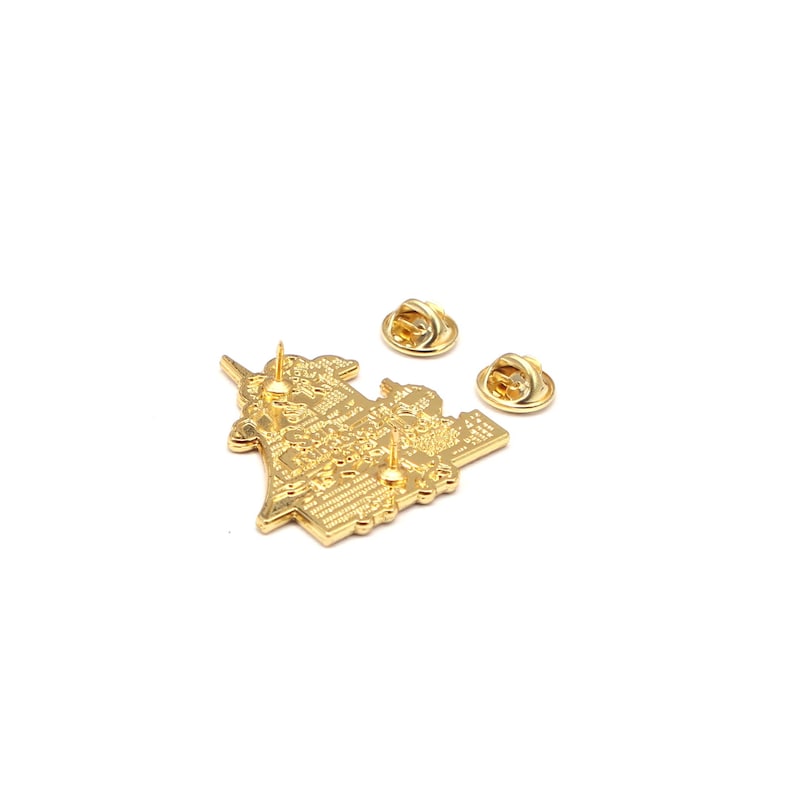 Op de afbeelding: Goudkleurige metalen pin met een gedetailleerd ontwerp, met twee pin backs. De pin heeft een complex patroon en textuur, waarschijnlijk een decoratief accessoire. De pin wordt op een witte achtergrond getoond.