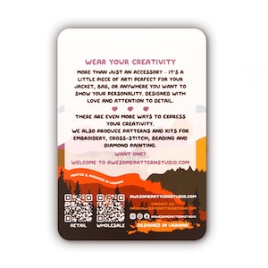 May include: A rectangular card with rounded corners, featuring text that reads "WEAR YOUR CREATIVITY." The card has a landscape design with a forest silhouette and text promoting patterns and kits for embroidery, cross-stitch, beading, and diamond painting.