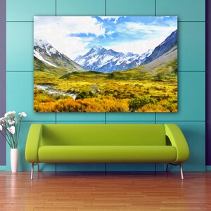 May include: A painting of a mountain range with snow-capped peaks and a valley with green grass and a river. The sky is blue with white clouds.