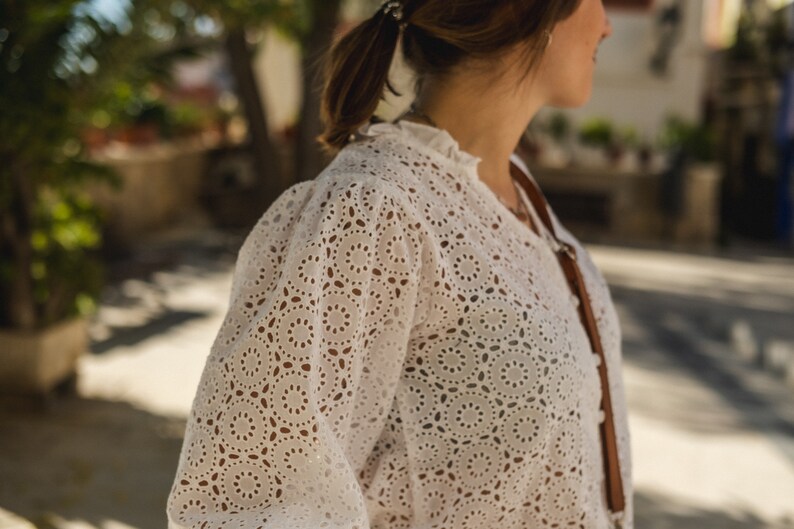 K&ouml;nnte beinhalten: Wei&szlig;e Blusenbluse mit zartem Muster. Die Bluse hat einen R&uuml;schenkragen und lange &Auml;rmel.
