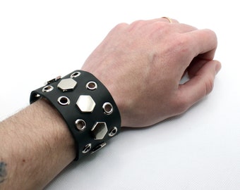 May include: Black leather cuff bracelet with silver hexagonal studs and eyelets.