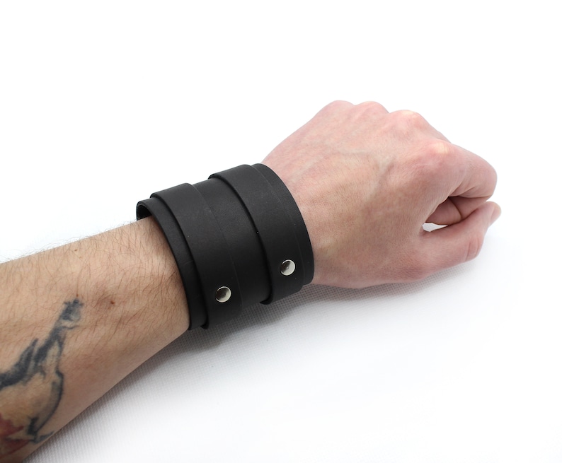 May include: A black leather cuff bracelet with two silver snaps.