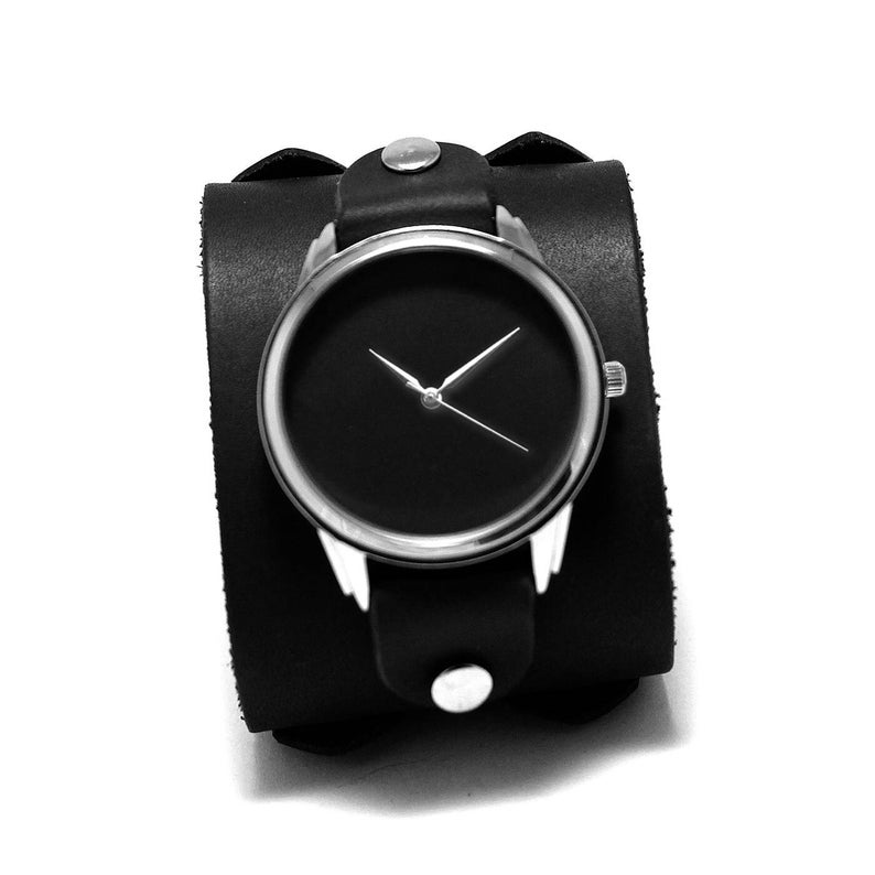 May include: A black leather cuff watch with a silver face and black hands.