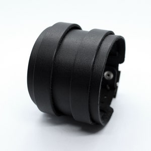 May include: A black leather bracelet with multiple layers and a metal clasp.