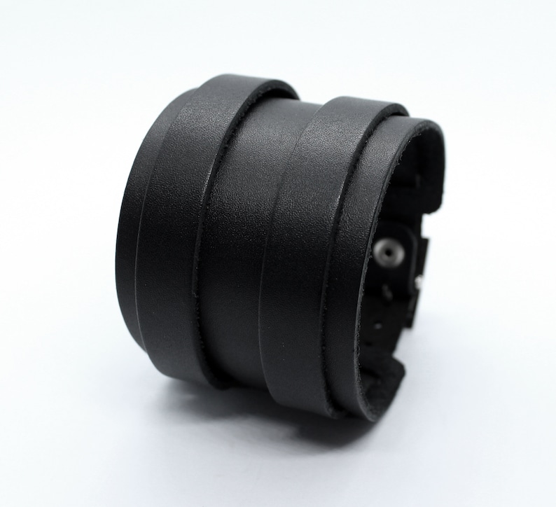 May include: A black leather bracelet with multiple layers and a metal clasp.