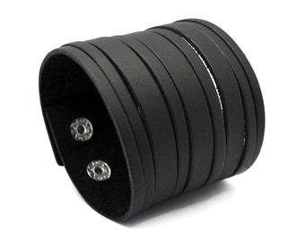 May include: A black leather cuff bracelet with multiple straps. The bracelet has a snap closure with two silver-colored snaps. The cuff is made of smooth, solid black leather.