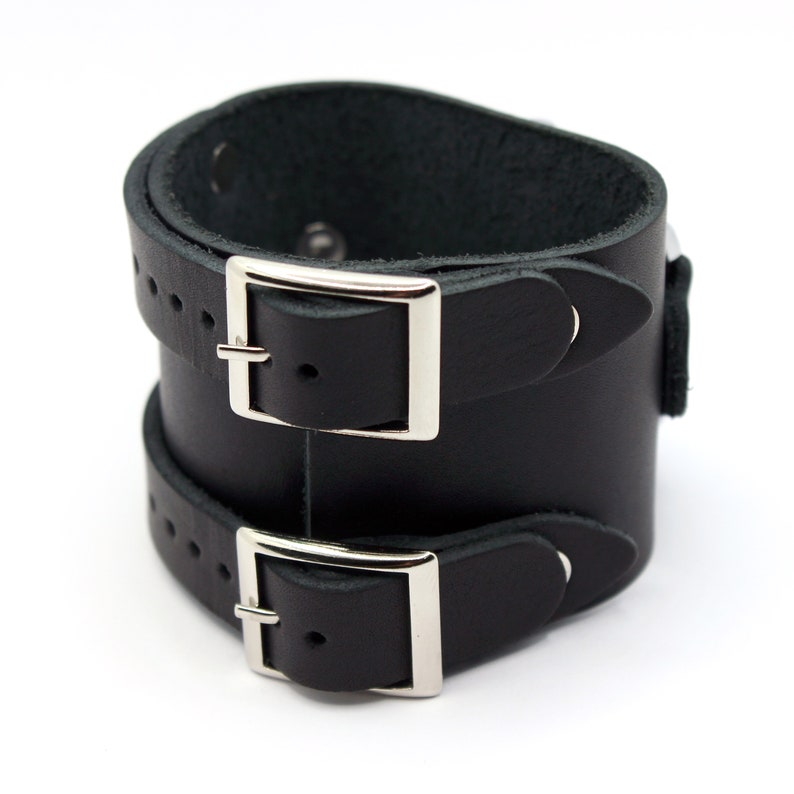 May include: Black leather cuff bracelet with two silver buckles.