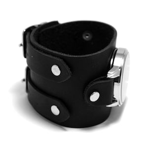 May include: Black leather cuff watch band with silver accents and a buckle closure.