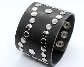 May include: A black leather cuff bracelet with silver studs. The bracelet is wide and has a row of studs down each side.