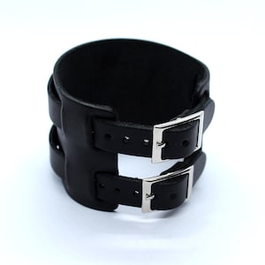 May include: Black leather cuff bracelet with two silver buckles.