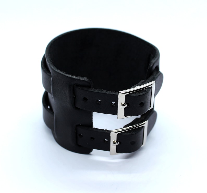 May include: Black leather cuff bracelet with two silver buckles.