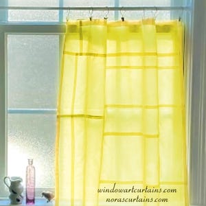 May include: A bright yellow, semi-sheer curtain panel featuring a grid-like pattern of horizontal and vertical bands. The curtain hangs from a rod with clips. The text windowartcurtains.com and norascurtains.com is printed on the fabric.