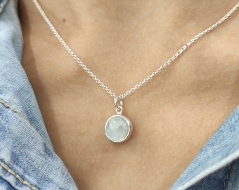 May include: A silver chain necklace with a round, white gemstone pendant.
