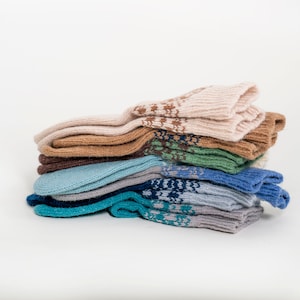 May include: A stack of colorful knitted socks in various shades of beige, brown, green, blue, and gray. Some socks feature patterned designs. The socks are neatly arranged, showcasing their textures and colors.