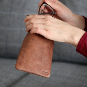 May include: Brown leather glasses case with the initials "SJW" embossed on the front.