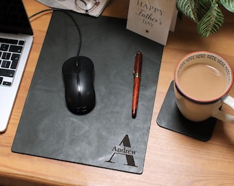 May include: A black mousepad with the name "Andrew" and the letter "A" engraved on it. A black computer mouse, a pen, and a cup of coffee are on the mousepad. A "Happy Father's Day" card is also visible.