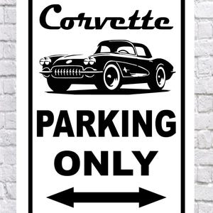 May include: A rectangular white metal sign with a black border. The sign features the word "Corvette" above a black and white illustration of a classic car. Below the car, the words "PARKING ONLY" are displayed with arrows.